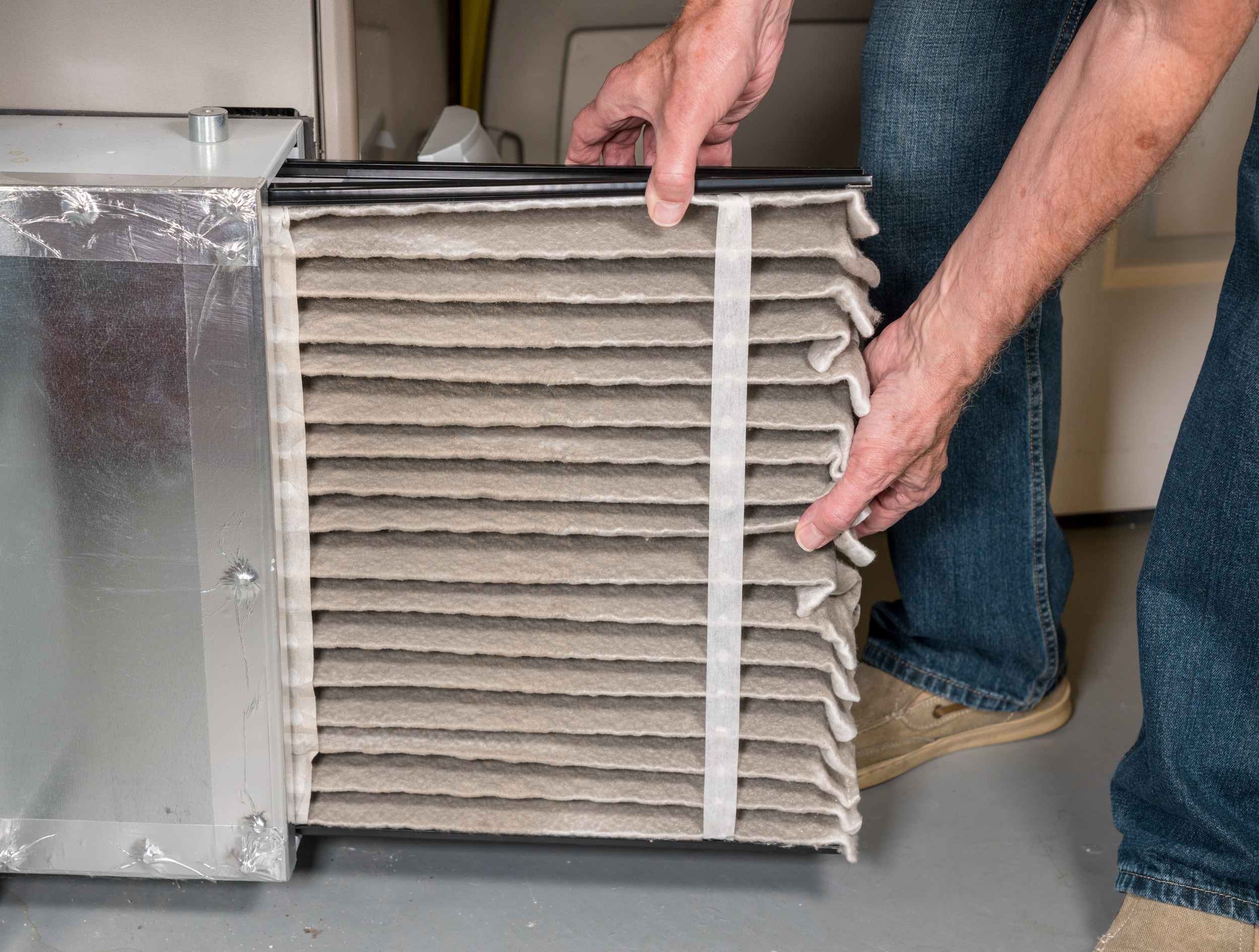 A person is replacing a dirty air filter in a HVAC system, highlighting the importance of regular maintenance for clean air quality.